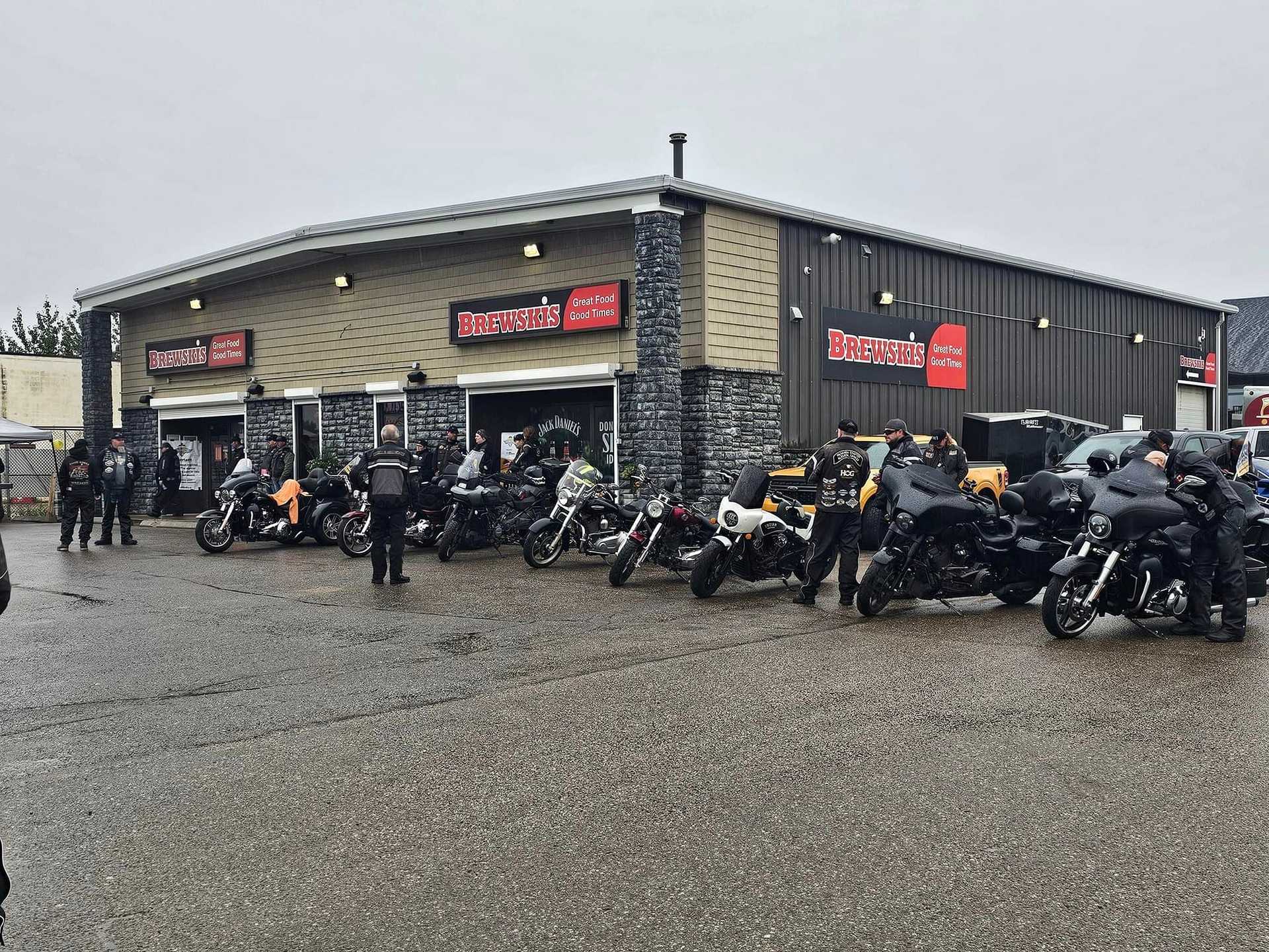 A group of motorcyclists gathered outside Brewsha's coffee shop on a cloudy day.