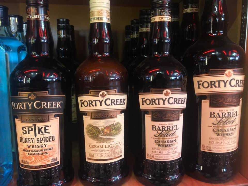 Four bottles of Forty Creek Canadian whisky on a shelf.
